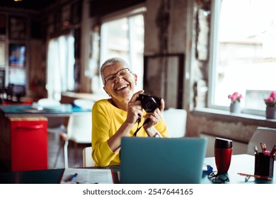 Senior woman reviewing photos on camera in office setting - Powered by Shutterstock