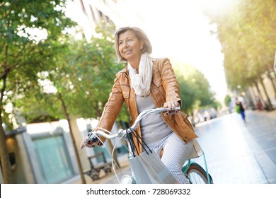 Senior Woman Riding City Bike In Town