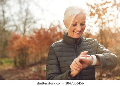 Senior Woman Running In Autumn Countryside Exercising Checking Smart Watch Fitness Activity App - Powered by Shutterstock