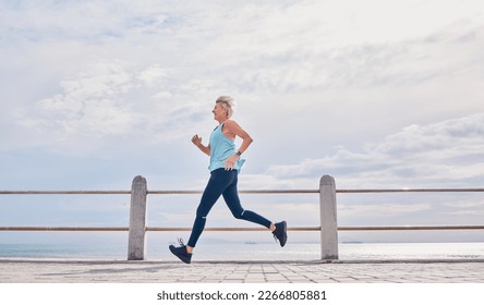 Senior woman running outdoor at on sky mockup at beach promenade for energy, health and cardio workout. Elderly female, exercise and runner at ocean for sports training, fitness and healthy marathon - Powered by Shutterstock