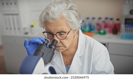 A senior woman scientist examines samples through a microscope in a modern laboratory - Powered by Shutterstock