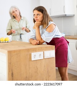 Senior Woman Scolding Her Adult Daughter Cooking Breakfast In Kitchen