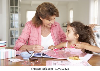 Senior Woman Scrapbooking With Granddaughter