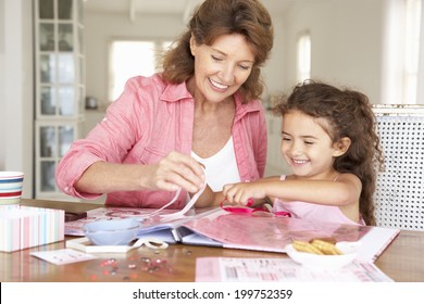 Senior Woman Scrapbooking With Granddaughter