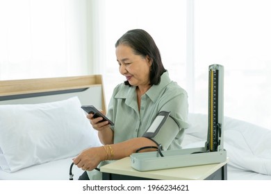 Senior Woman Setting Up BP Or Blood Pressure Medical Equipment Of Check Up At Home By Yourself.