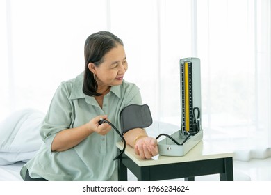 Senior Woman Setting Up BP Or Blood Pressure Medical Equipment Of Check Up At Home By Yourself.