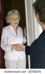 Senior Woman Shaking Hands At Her Front Door