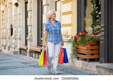 Senior Woman With Shopping Bags Walking Beside Shopping Window