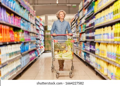 Senior Woman Shopping With A Full Shopping Cart In The Aisle From The Supermarket