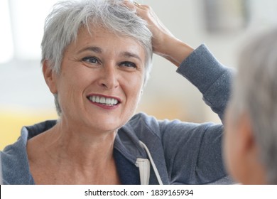 Senior Woman With Short Grey Hair Putting Make-up On