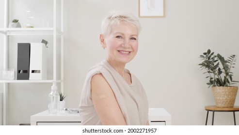 Senior Woman Showing Her Arm With Band Aid After Coronavirus Covid-19 Vaccine Injection. Covid Vaccination Concept