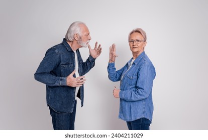 Senior woman showing stop gesture to frustrated husband while having argument on white background - Powered by Shutterstock