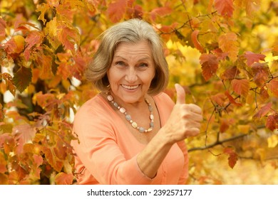 Senior woman showing thumb up in the park in autumn