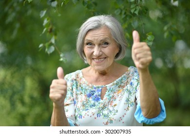 Senior woman showing thumbs up in the park