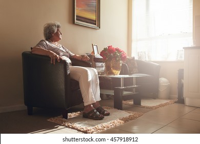 Mujer mayor sentada sola en una silla en casa. Mujer jubilada relajándose en el salón.