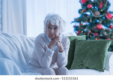 Senior Woman Sitting Alone On Sofa, Christmas Tree In Background