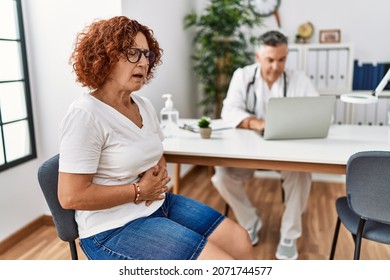 Senior woman sitting at doctor appointment with hand on stomach because indigestion, painful illness feeling unwell. ache concept. 
