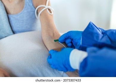 Senior Woman Sitting In The Hospital Chair While Receiving IV Infusion In Medicine Center