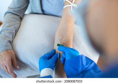 Senior Woman Sitting In The Hospital Chair While Receiving IV Infusion In Medicine Center