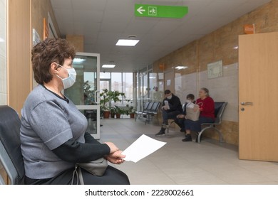 A senior woman sitting in hospital waiting for a doctor's appointment. Patients In Doctors Waiting Room - Powered by Shutterstock