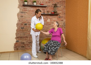 Senior Woman Sitting On A Chair And Holding Spiky Ball During Physiotherapy