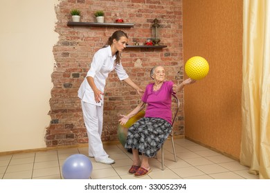 Senior Woman Sitting On A Chair And Holding Spiky Ball During Physiotherapy