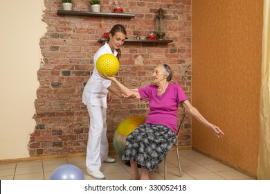 Senior Woman Sitting On A Chair And Holding Spiky Ball During Physiotherapy