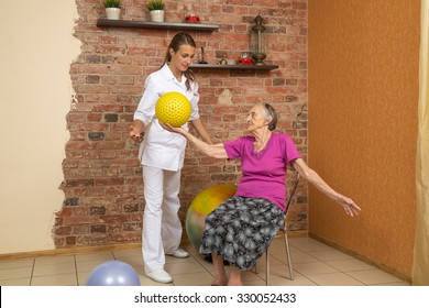 Senior Woman Sitting On A Chair And Holding Spiky Ball During Physiotherapy