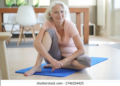 Senior Woman Sitting On Gym Mat At Home