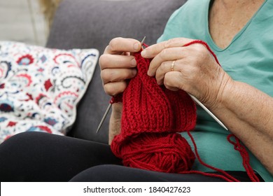 Senior woman sitting on sofa and knitting with red wool. Hand made wool item. Craft and DIY concept.
 - Powered by Shutterstock