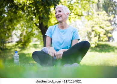 Senior Woman Sitting And Resing After Workout In Park