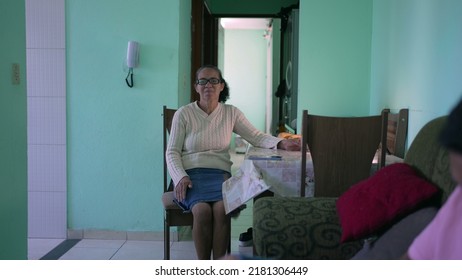 Senior Woman Sitting At Table. South American Hispanic Mature Older Woman At Home