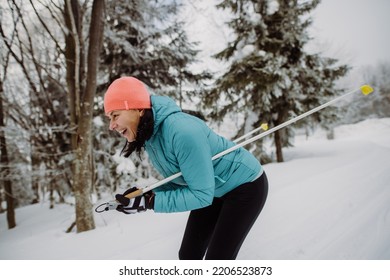 Senior Woman Skiing In The Middle Of Snowy Forest.