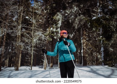 Senior Woman Skiing In The Middle Of Snowy Forest.