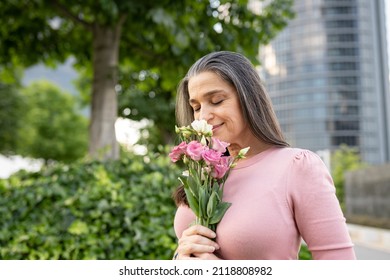 Senior Woman, Smelling Some Flowers In The City