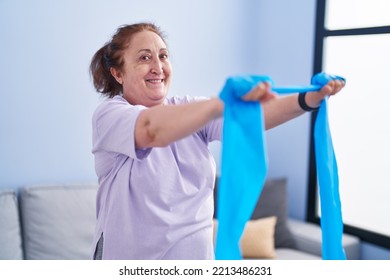 Senior Woman Smiling Confident Using Elastic Band Training At Home