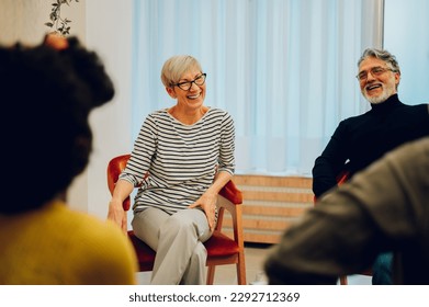 Senior woman smiling with other patients while participating in group therapy session. Telling stories during psychological rehab session. Overcoming problems with a help of a professional. - Powered by Shutterstock