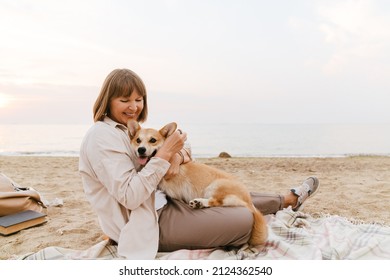 Senior woman smiling while resting with her dog on sandy beach - Powered by Shutterstock