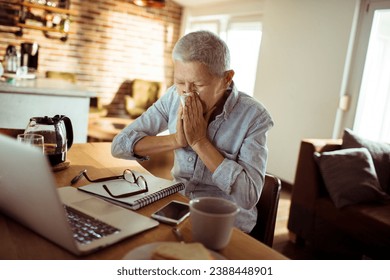 Senior woman sneezing blowing nose in tissue paper at home - Powered by Shutterstock