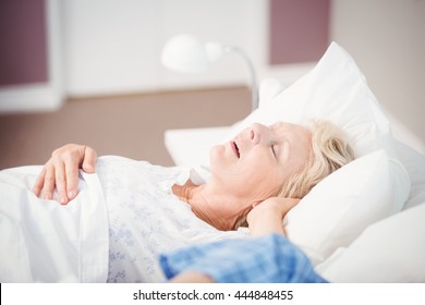 Senior Woman Snoring Next To Husband On Bed At Home