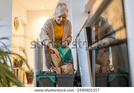 Senior woman sorting garbage in recycling bins at home
