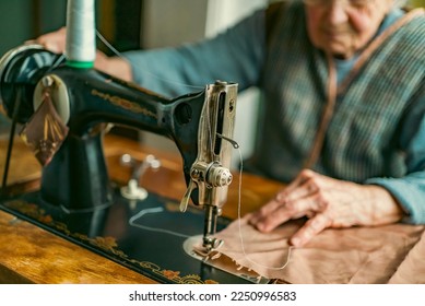 Senior woman in spectacles use sewing machine. wrinkled hands of the old seamstress.elderly woman . Old sewing machine Classic retro style manual sewing machine ready for sewing work.  - Powered by Shutterstock