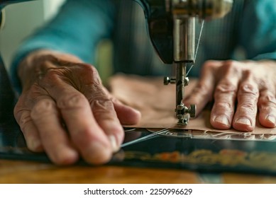 Senior woman in spectacles use sewing machine. wrinkled hands of the old seamstress.elderly woman . Old sewing machine Classic retro style manual sewing machine ready for sewing work.  - Powered by Shutterstock