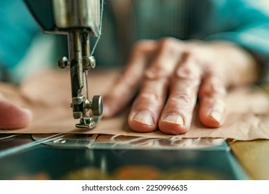 Senior woman in spectacles use sewing machine. wrinkled hands of the old seamstress.elderly woman . Old sewing machine Classic retro style manual sewing machine ready for sewing work.  - Powered by Shutterstock