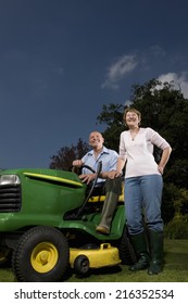 Senior Woman Standing Next To Man On Riding Lawn Mower