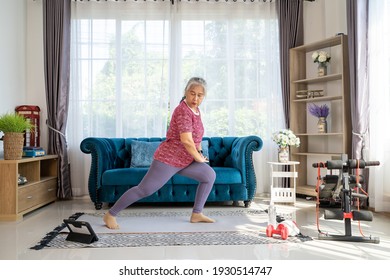 Senior woman stretch  back and leg muscles. Reduce knee pain, Training exercise online with tablet In Living Room During Quarantine