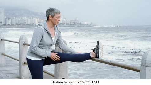 Senior woman, stretching and fitness at beach with peace, leg flexibility or running preparation. Retired athlete, warm up or muscle tension relief at seaside for exercise, wellness or care in Italy - Powered by Shutterstock