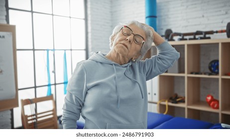 A senior woman stretching her neck in a physiotherapy clinic, showcasing wellness and active aging. - Powered by Shutterstock