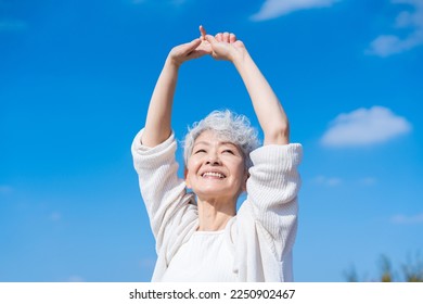 A senior woman stretching outside with a smile - Powered by Shutterstock