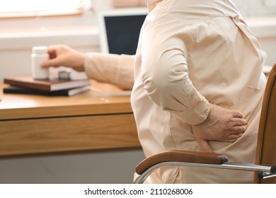 Senior Woman Suffering From Back Pain In Chair At Home, Closeup